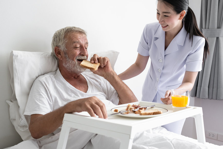 senior man with smiling nurse, takes care breakfast and discussi